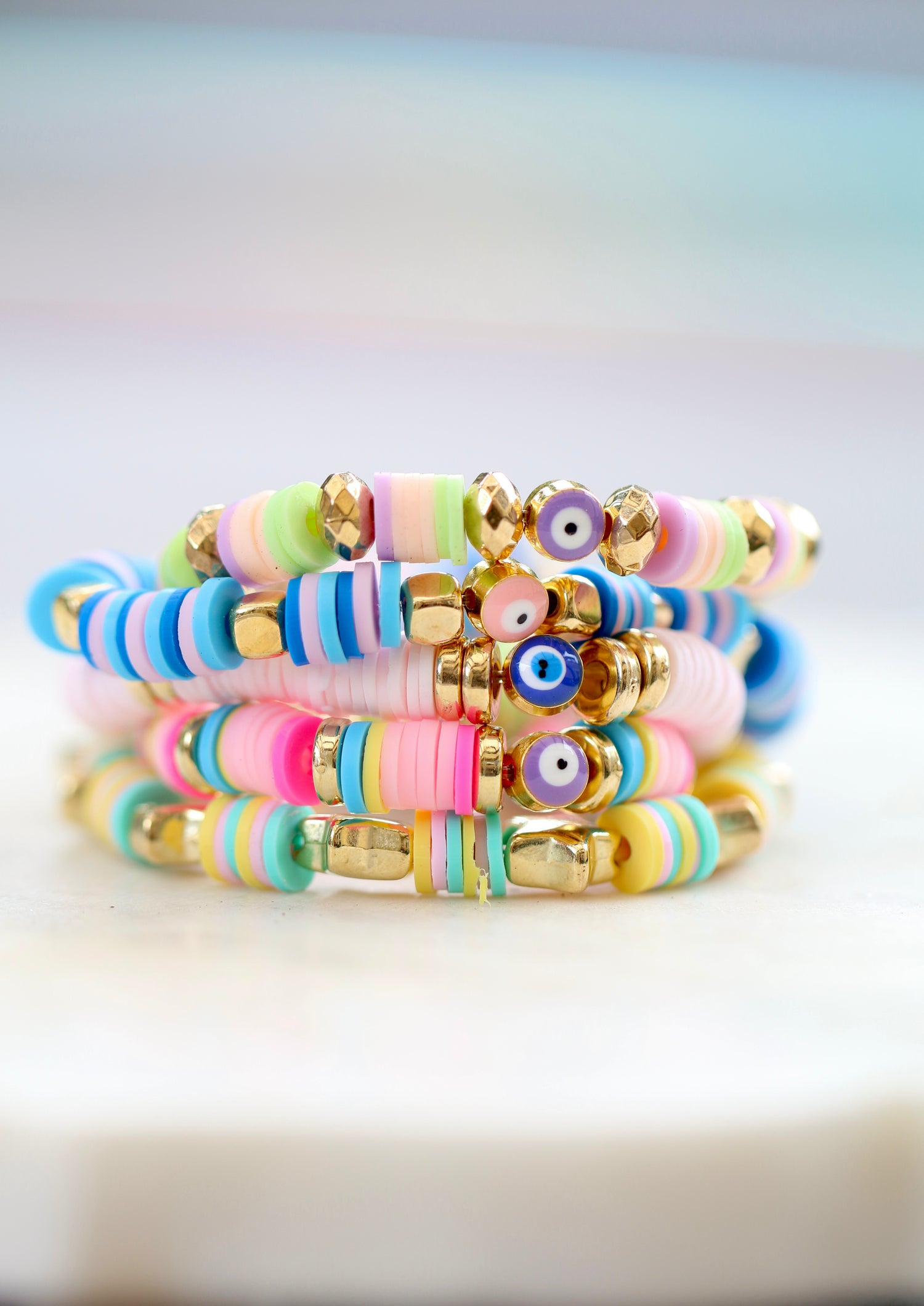 bright photo focusing on five colorful bracelets stacked on top of each other on a white marble table